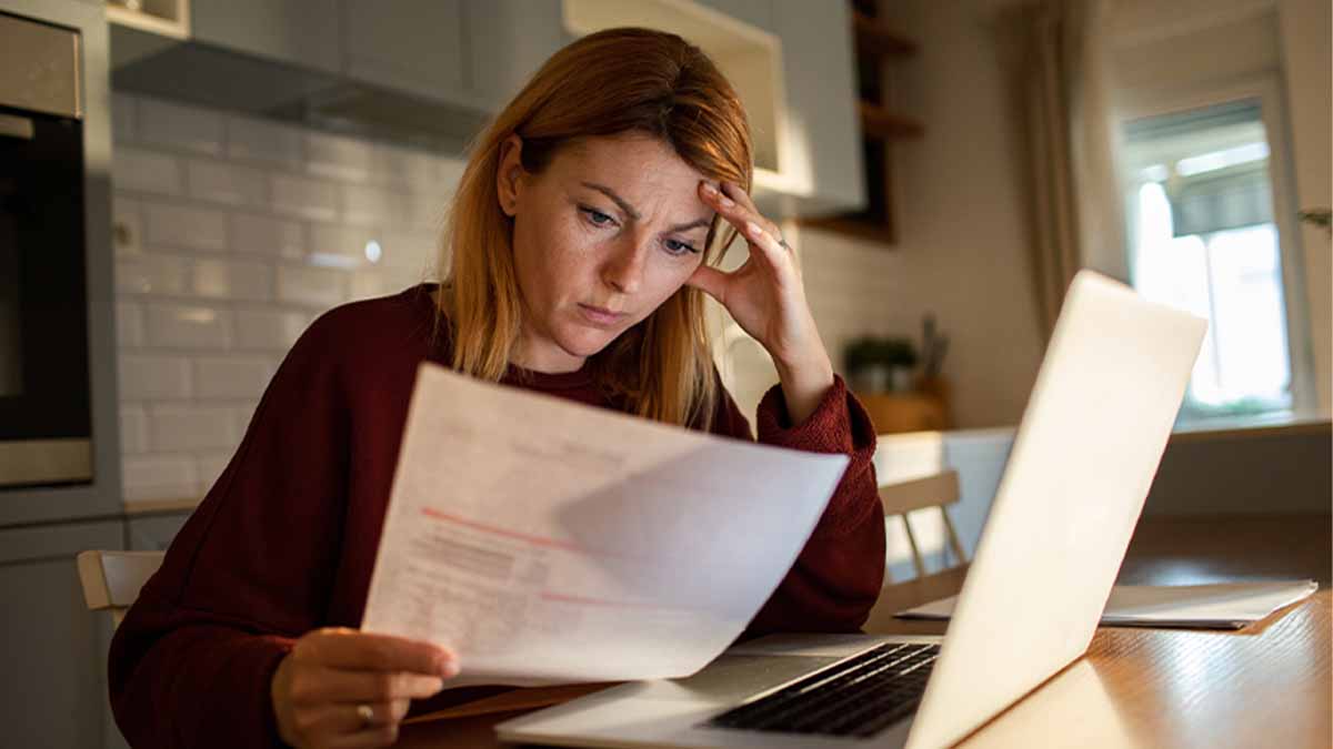 Mulher jovem a analisar fatura com computador portátil